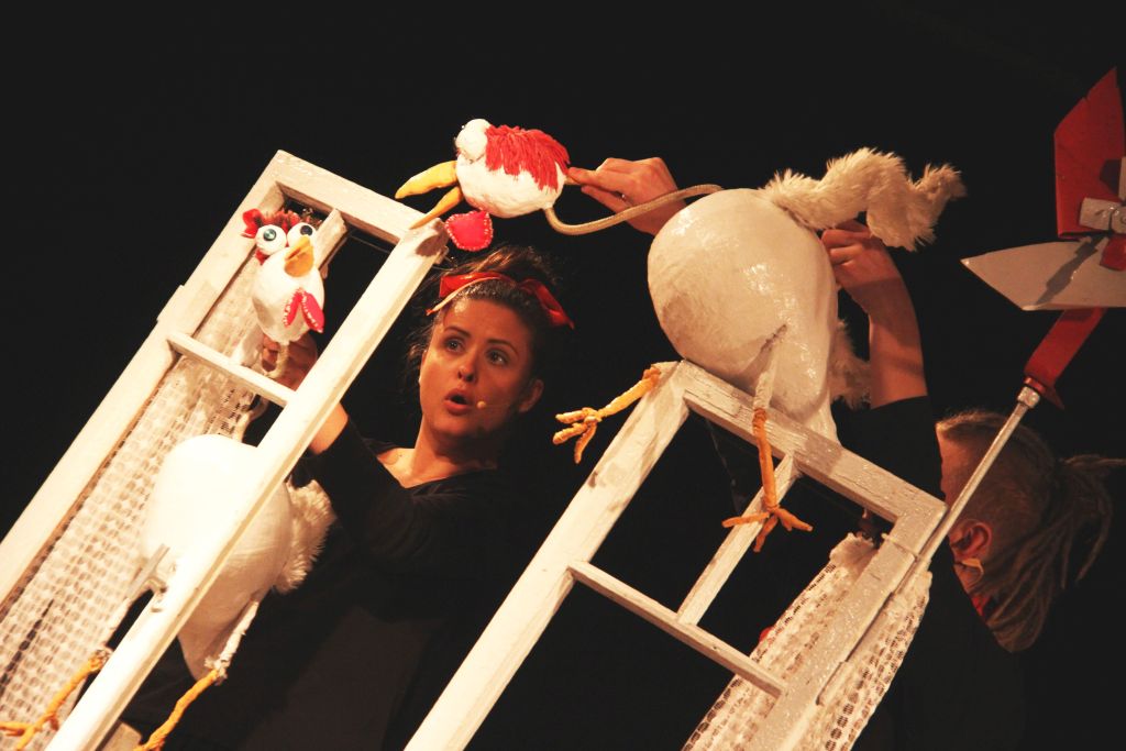 Aktorzy z kukiełkami kury podczas występu na scenie